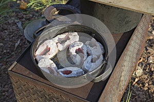 Fish fried in a frying pan on a wood-burning stove