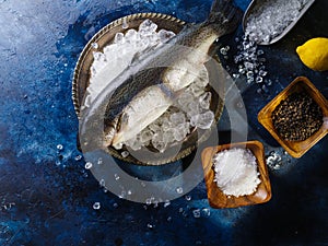 Fish on ice cubes, salt and spices. Preparation of fish and seafood dishes. High angle view. Restaurant, hotel, cafe, fish market