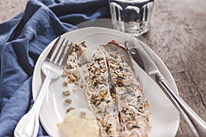 Fish mackerel baked with herbs, mashed potatoes, pesto sauce served on a white plate on a wooden antique background, next to a bl