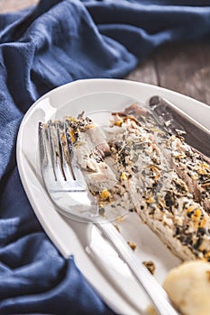 Fish mackerel baked with herbs, mashed potatoes, pesto sauce served on a white plate on a wooden antique background, next to a bl