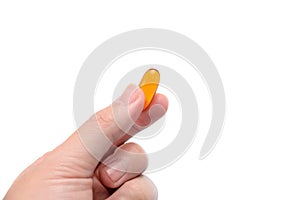 Fish oil capsule in fingers on white background