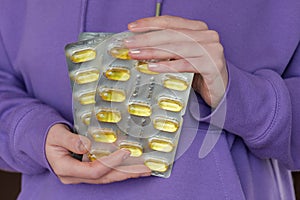 Fish oil capsules in blisters set in hands .Dietary supplements and vitamins in womens nutrition. Fish oil for womens