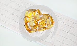 Fish oil capsules on cardiogram ECG, healthy heart concept