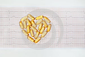 Fish oil capsules on cardiogram ECG, healthy heart concept