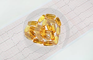 Fish oil capsules on cardiogram ECG, healthy heart concept