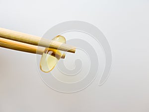 Fish oil capsules with Chinese chopsticks. Capsules with fish oil. Omega 3 fish oil capsules on a white background. High