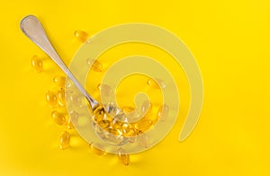 Fish oil capsules in a spoon. Healthy lifestyle with natural supplements. Isolated on yellow color background. Copy space for text