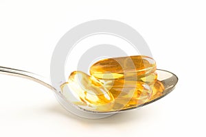 fish oil capsules in a spoon on white