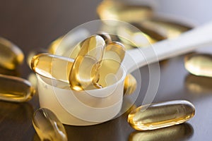Fish oil capsules on wooden background and texture, vitamin D supplement
