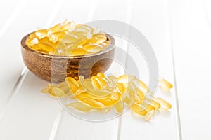 Fish oil capsules. Yellow omega 3 pills in bowl on white table