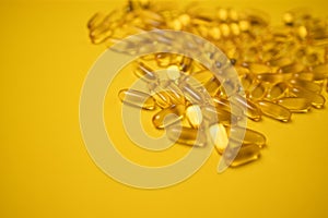 Fish oil omega 3 gel capsules isolated on yellow background. Healthcare concept
