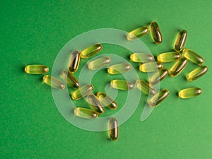 Fish oil omega 3 capsules on green background