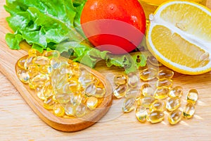Fish oil, soft capsule, omega 3, supplement food vitamin D capsules with vegetables and fruit greens tomato lemon on wood . still