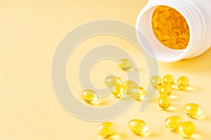 Fish oil soft gel supplement capsules source of omega 3 and vitamins A, E on yellow background