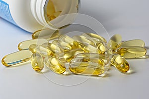 Fish oil softgel capsules scattered on a white table, focus on foreground