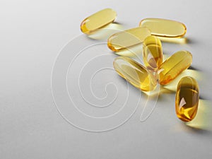 Fish oil. Yellow softgels lie on a white or light gray surface. Vitamins and a healthy lifestyle. Background or backdrop. Copy