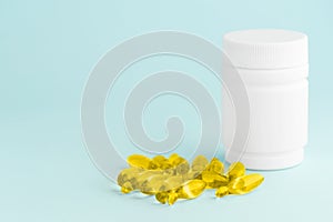 Fish oil yellow supplement capsules omega-3 isolated and white plastic container bottle on blue surface. Health care