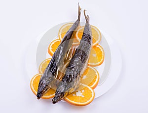 Fish on orange slices laid out on a white plate