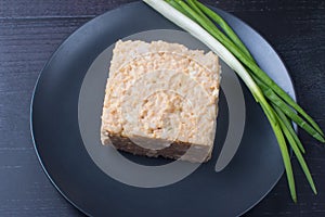 Fish salad of rice and pink salmon on a plate with green onions.