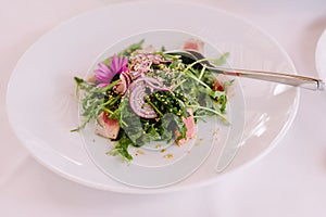 Fish salad with rukkola and onion rings. European cuisine. Exquisite food in the restaurant