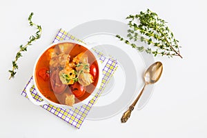 Fish soup with cod, tomato, onion, garlic and thyme in bowl on white table, top view