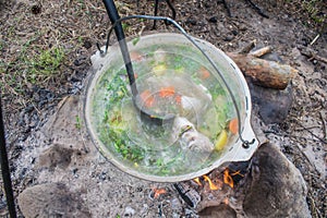 Fish soup cooking in a pot on a fire in the forest by the sea