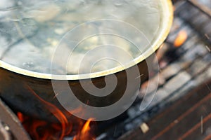 Fish soup with grayling cooked in large castiron pot at bonfire