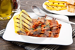 Fish soup with grilled polenta on white dish