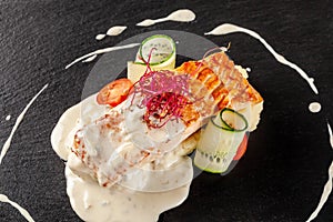 Fish steak from red fish salmon or trout, with a side dish of mashed potatoes, cherry tomatoes, cucumber and creamy sauce