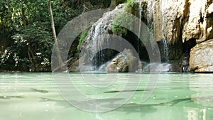 Fish swimming under water around Erawan waterfall , popular famous tourist attraction in Kanchanaburi, Thailand. Erawan waterfall