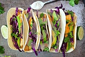 Fish tacos with red cabbage lime slaw on rustic tray