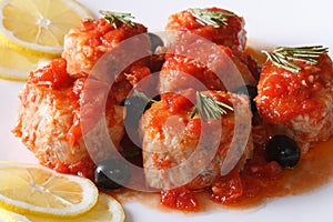 Fish in tomato sauce with olives on the plate closeup horizontal