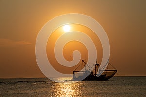 A fish trawler in the North Sea, Waddenzee at sunset