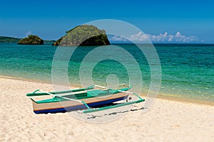 Fishboat on sand and two small islands on tropic turquoise sea