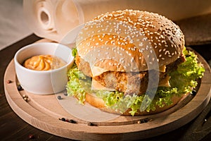 Fishburger with fresh salad and cheese on round wooden board