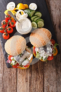 Fishburger with herring, gravy and fresh vegetables close-up. ve