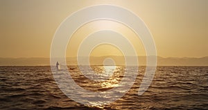 Fisher with a cap on a boat in a Myanmar water body in a sunset