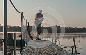 Fisher fishing in foggy morning. Man with fish rod resting on lake in mist