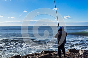 Fisher man fishing with spinning rod at ocean