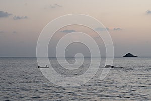 A Fisher man sailing on his boat at majali beach after sunset.