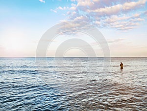 Fisher man stay in the water and pulling bait on his fishing rod. Baltic shore