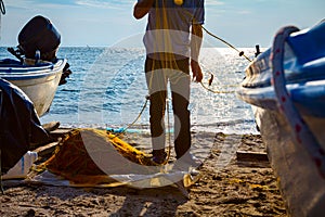 Fisher pile up fishing net at sandy beach