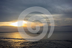 Fisherboat in horizon on sunset at sea in Bali, Indonesia