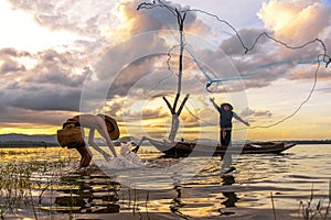 Fisherman action when fishing net on lake in the sunshine morning and silhouette fisherman on the boat,