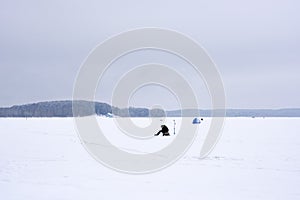 Fisherman alone on a deserted frozen lake