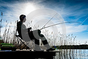 Fisherman or Angler at lake in Sunrise backlit photo