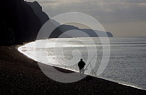 Fisherman angling on beach