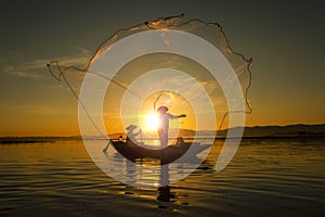 Fisherman of asian people at Lake in action when fishing during sunrise