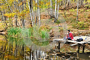 Fisherman in autumn forest catches the fish in the lake