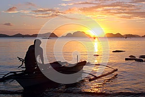 Fisherman in a banka, traditional filipino boat, at sunset, the Philippines